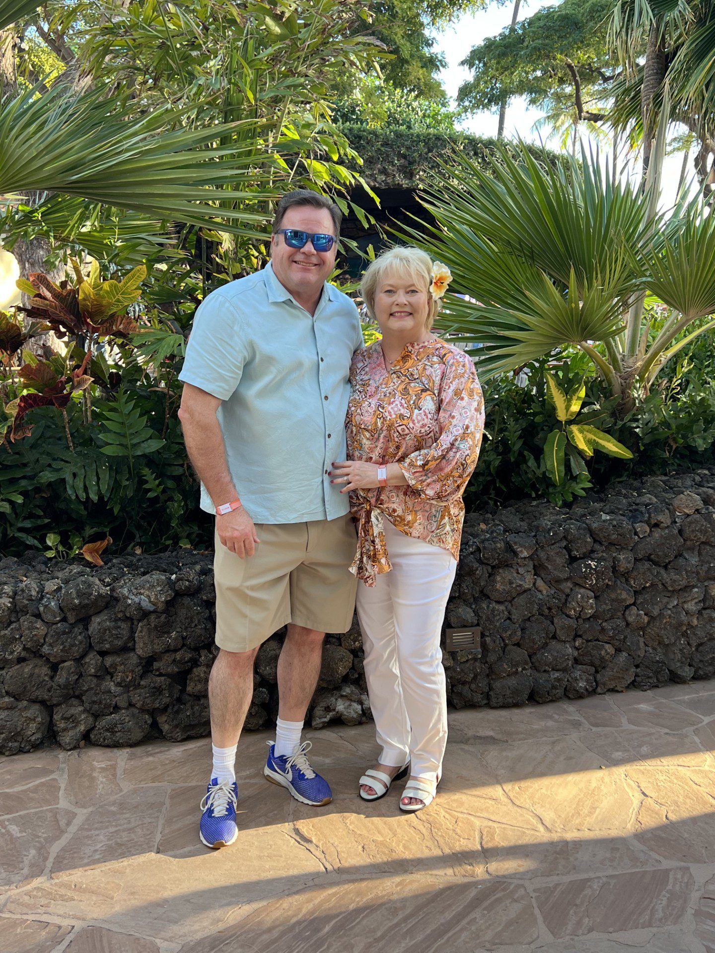 a smiling couple posing for a photo with tropical vegetation